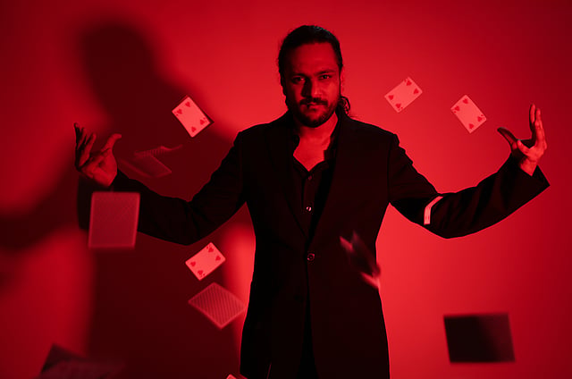Karan Singh Magic surrounded by playing cards, photographed in red light